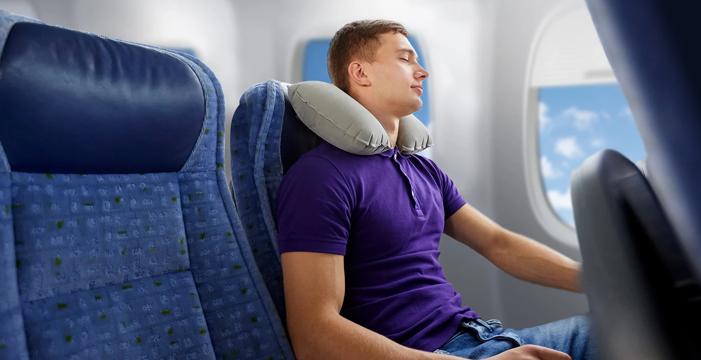 Young man sleeping on a plane to avoid jet lag.